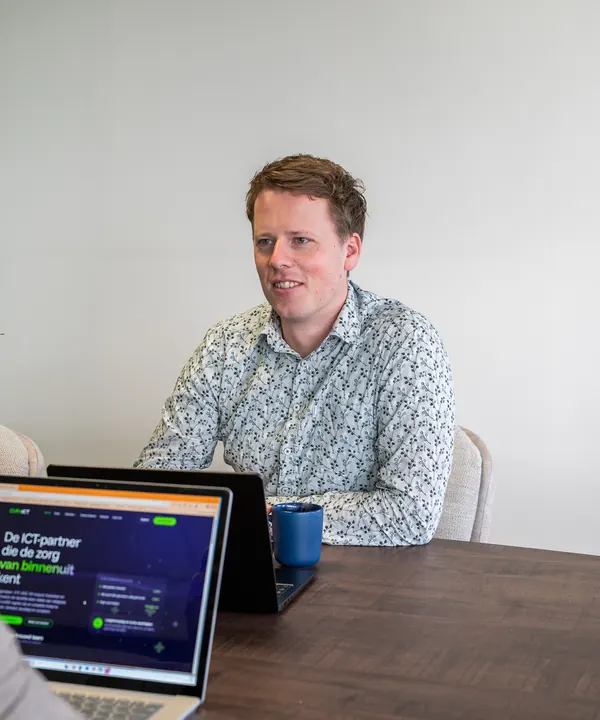 Sander van Cura ICT in gesprek aan tafel, met de website open op een laptop