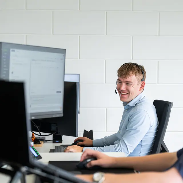 Lachende servicedeskmedewerker van Cura ICT met headset